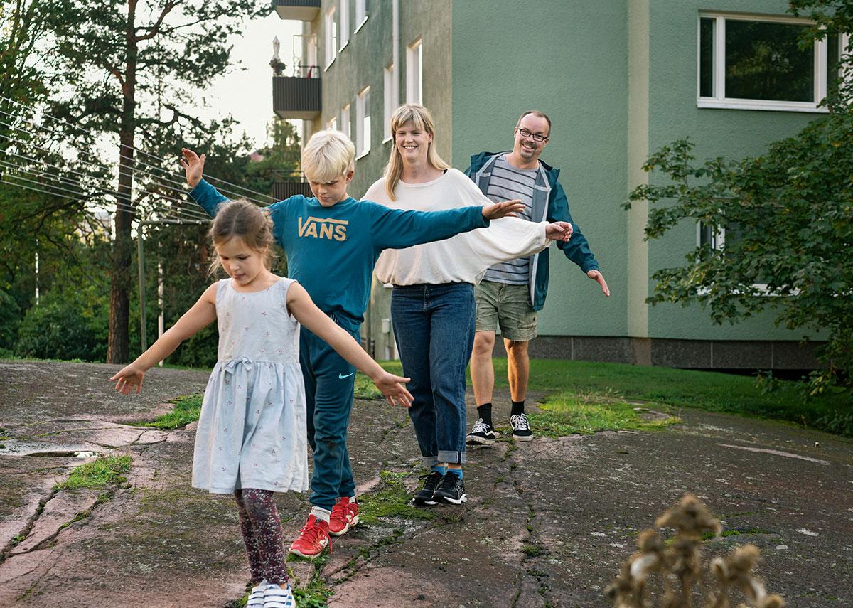 Perhe tasapainoilee kalliolla.
